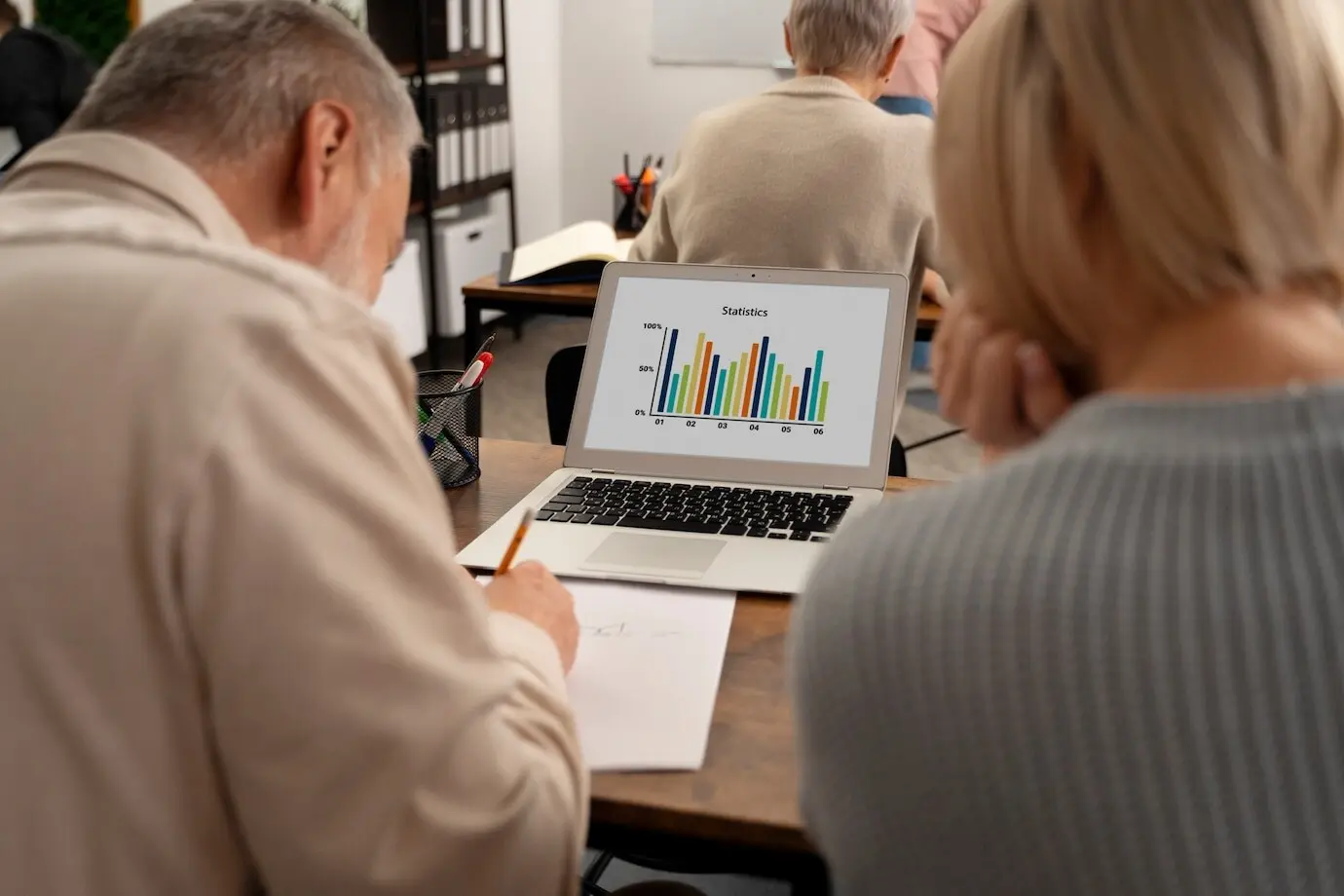 Пожилые люди в школе во время урока с ноутбуком.